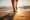 Close-up of female legs getting out of the sea water and walking on sandy beach at beautiful sunset